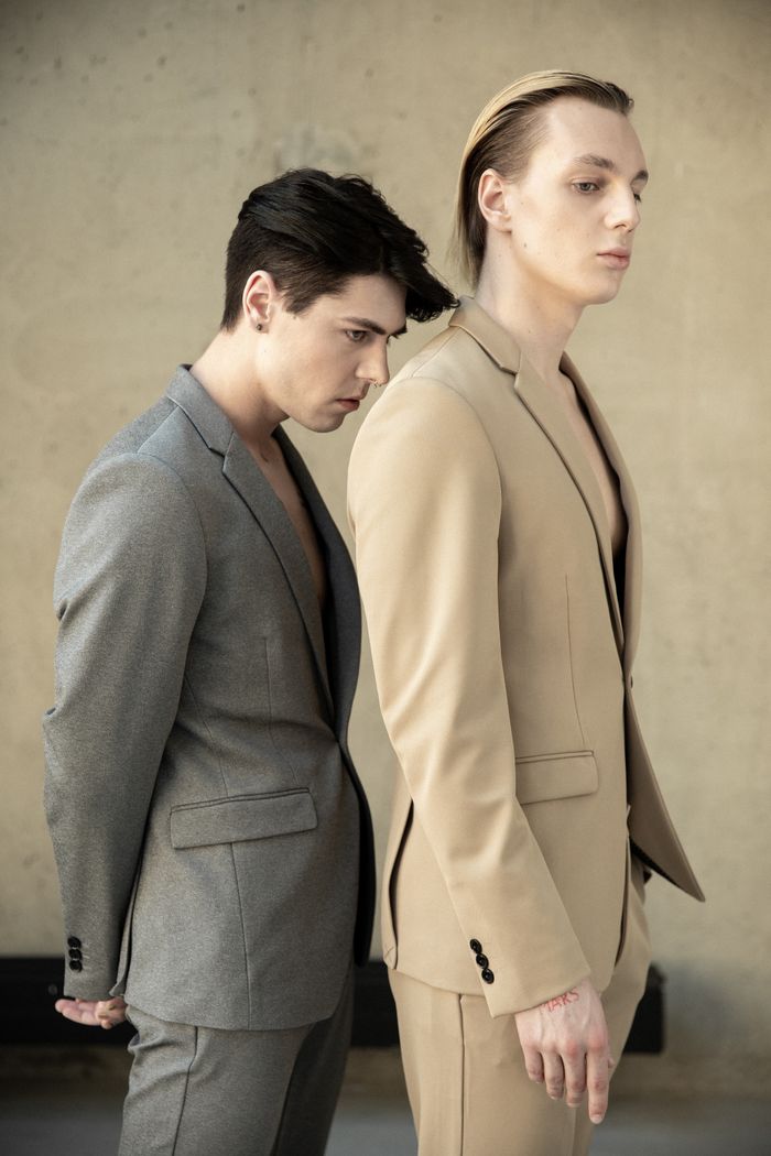 Stylish portrait of two men in elegant suits, showcasing modern fashion trends in a minimalist setting.